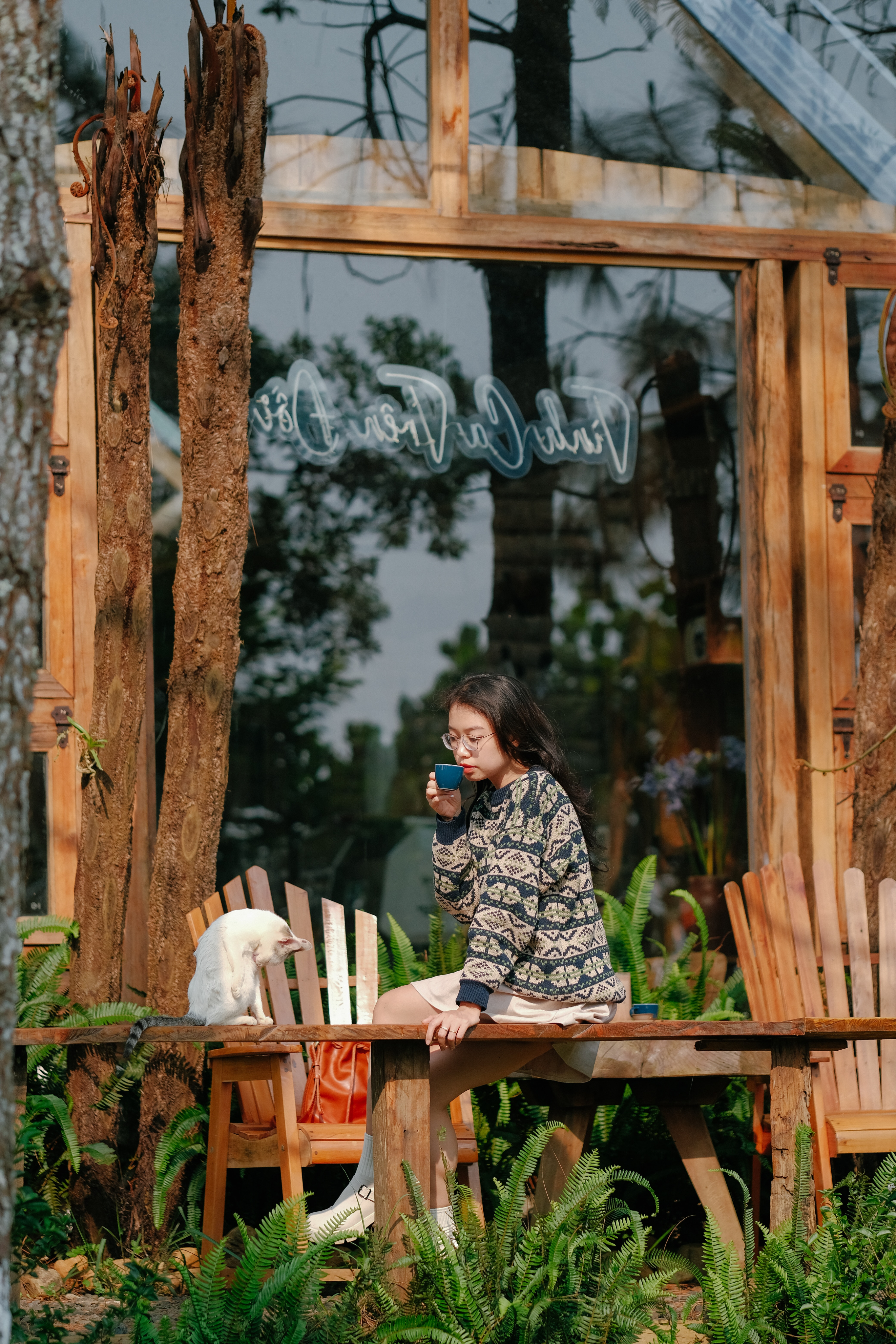 A lady enjoying a coffee outside with a cat
